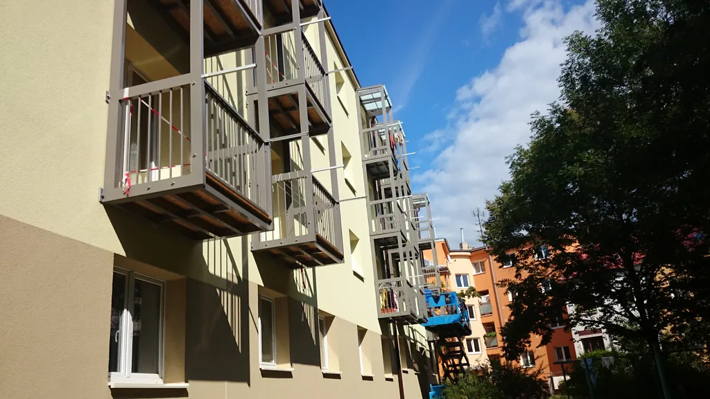 Bytový dům s novou fasádou a zavěšenými balkony